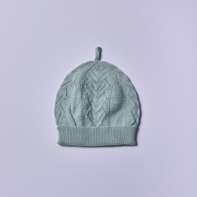 Gorro de malha verde claro com padrão em relevo e argola no topo