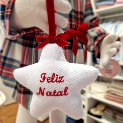 Ornamento de Natal em forma de estrela branca com texto vermelho 'Feliz Natal'