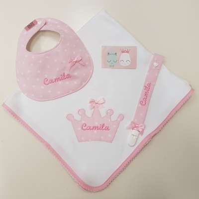 Conjunto bebé com babete rosa, manta branca com coroa rosa, fita para chucha rosa e cartão com pinguins