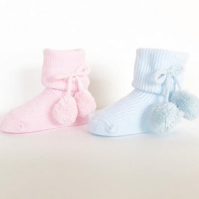 Meias infantis rosa e azul com pompons sobre fundo branco