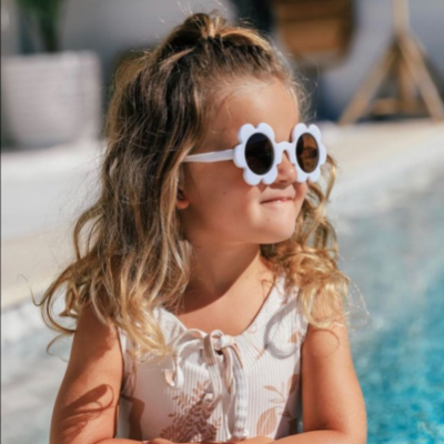 Menina com óculos de sol brancos e fato de banho junto a uma piscina