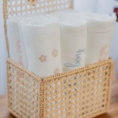 Cesto de verga com panos brancos bordados enrolados