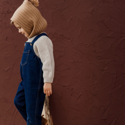 Criança com roupa casual de inverno em fundo castanho texturado
