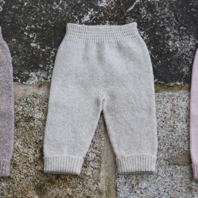 Calças de malha cinza claro para bebé sobre pedra rugosa