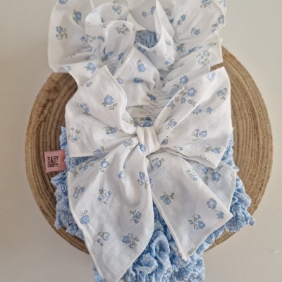Roupa de bebé azul claro e branca com padrão de flores azuis e laço grande