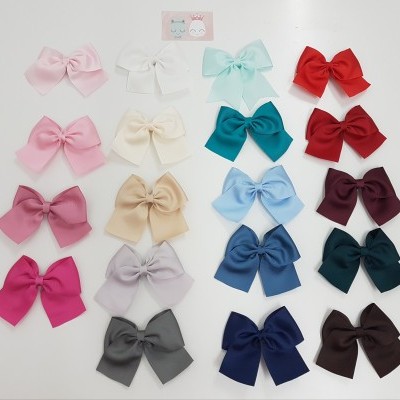 Vários laços coloridos organizados em filas sobre superfície branca com cartão ilustrado