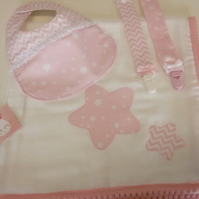 Conjunto bebé rosa e branco com babete, manta e fitas de chupeta, padrões de estrelas e chevron.