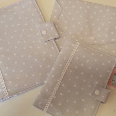 Conjunto de capas cinza com estrelas brancas, botões de pressão e renda, com cartão rosa ao lado