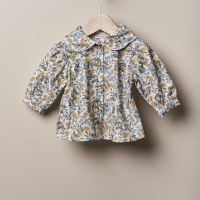 Blusa infantil floral pendurada num cabide de madeira
