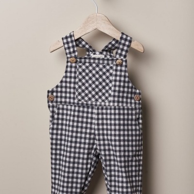 Jardineiras de bebé xadrez preto e branco penduradas num cabide de madeira