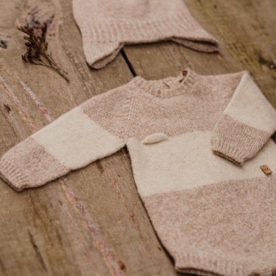 Conjunto de bebé com body e gorro de malha bege e cinzento sobre madeira rústica