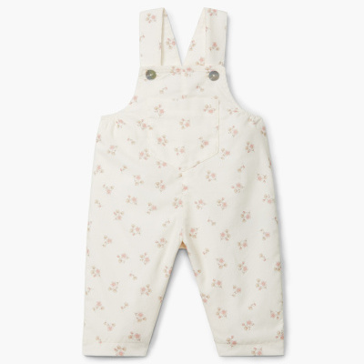 Macacão infantil branco com padrão floral e alças largas com botões.