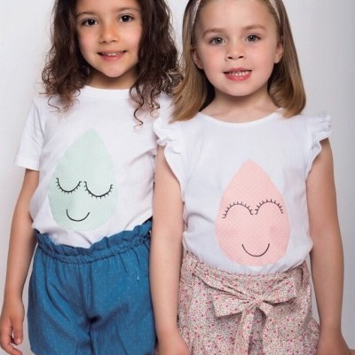 Duas crianças com t-shirts brancas estampadas e calções coloridos