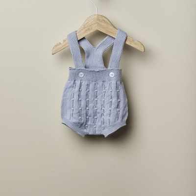 Jardineira de bebé cinzenta clara em malha pendurada num cabide de madeira