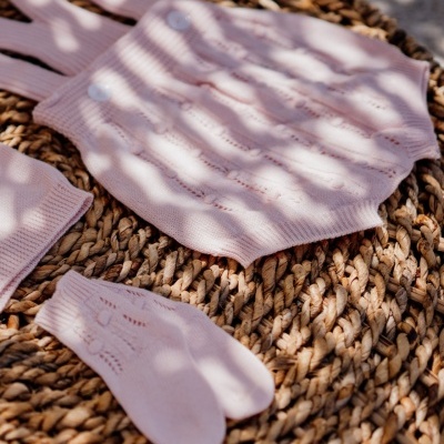 Conjunto de roupa de malha rosa claro com padrão rendado em superfície entrelaçada de palha