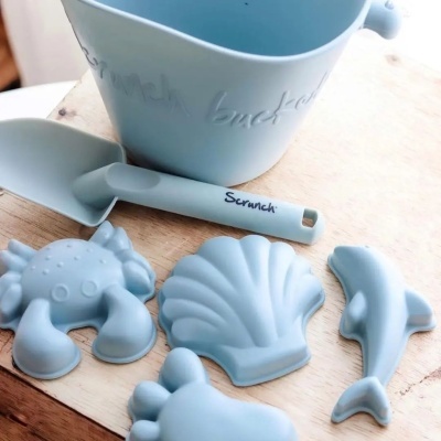 Conjunto azul de balde e acessórios de praia em silicone com formas de caranguejo, concha, golfinho e tartaruga.