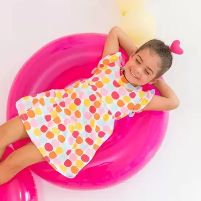 Criança sorridente deitada em colchão insuflável rosa