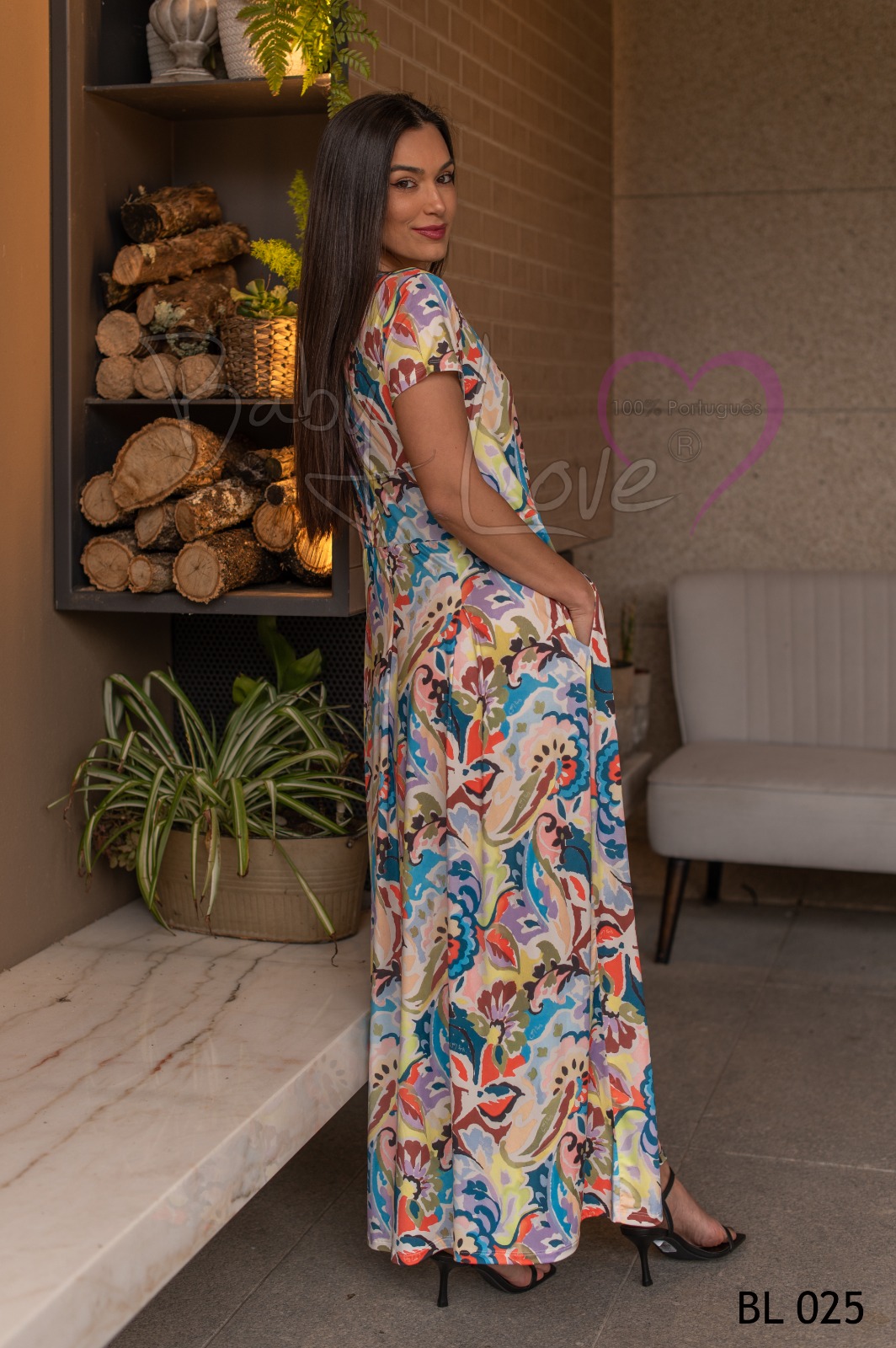 VESTIDO C/ PREGAS Vestido comprido colorido abstrato usado por modelo com sapatos pretos em ambiente interior