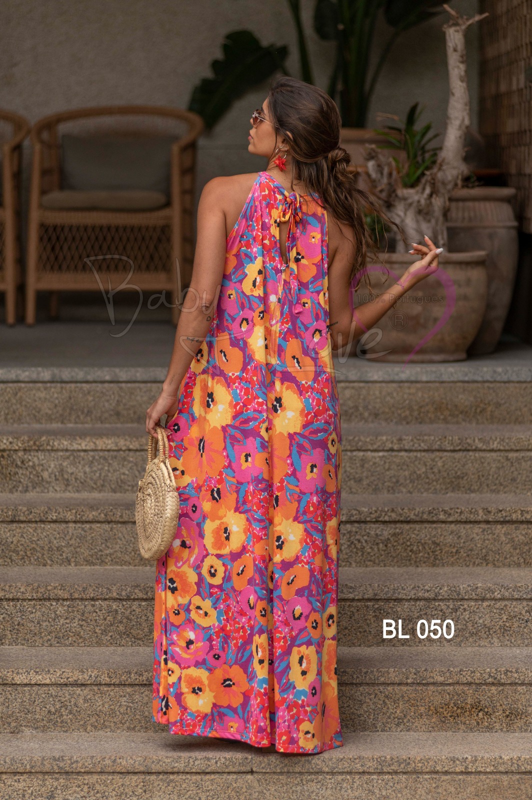 VESTIDO COMPRIDO PADRÃO FLORAL Vestido longo colorido com padrão floral em escadaria com plantas e cadeiras