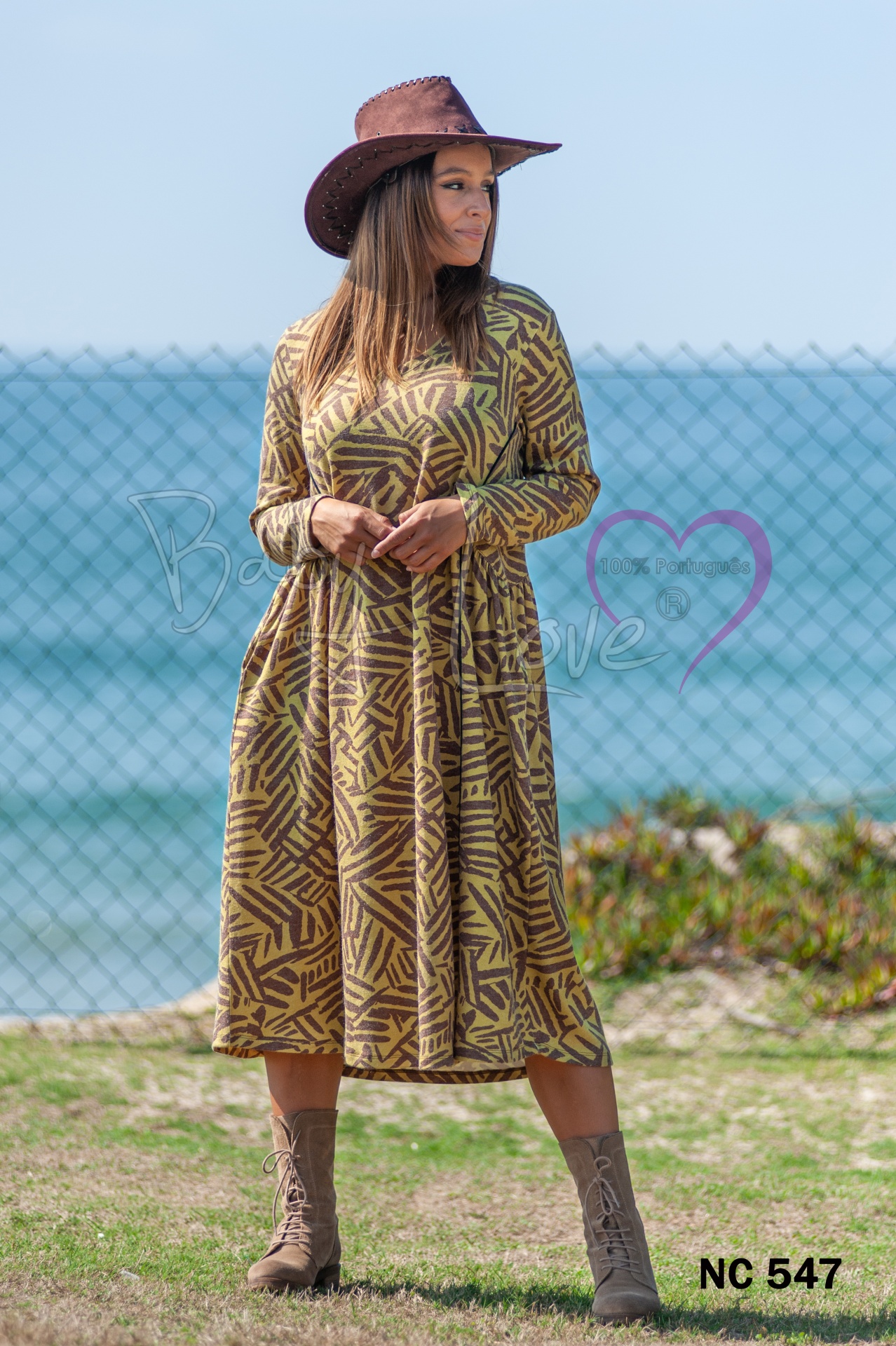 VESTIDO Vestido midi amarelo com padrão geométrico castanho usado ao ar livre com mar ao fundo
