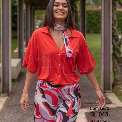 Mulher com camisa vermelha e calças estampadas abstratas ao ar livre