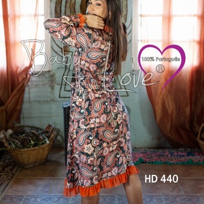 Vestido comprido com padrão paisley e ribetes laranja usado por mulher em ambiente interior