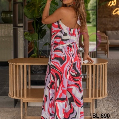 Macacão colorido de padrão abstrato vermelho, branco e preto com recorte numa alça usado por mulher