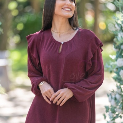 Vestido feminino bordô com folhos nos ombros e botão branco na gola, em ambiente exterior