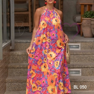 Vestido longo halter floral rosa e laranja usado por mulher com acessórios, em escadas exteriores