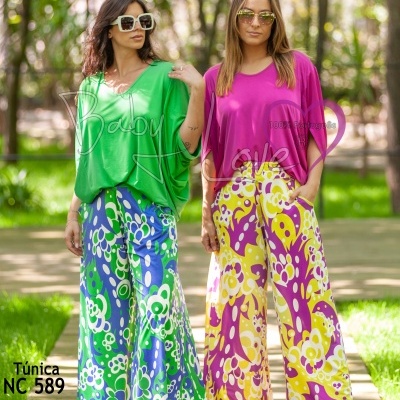 Duas mulheres com túnicas e pantalonas florais coloridas num parque