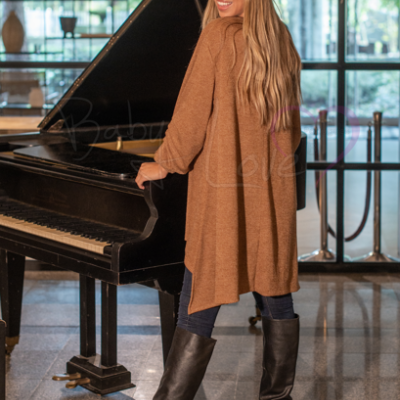 Mulher com boina castanha e casaco castanho junto a piano preto numa sala moderna