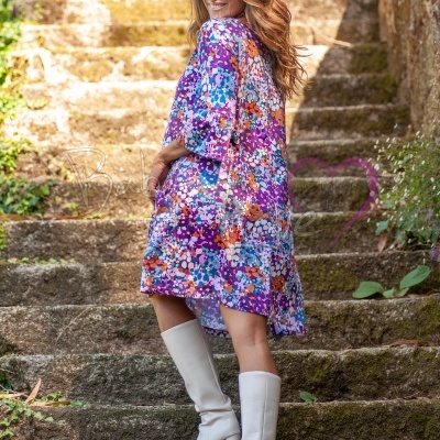 Mulher de vestido floral colorido e botas brancas em escadas de pedra ao ar livre