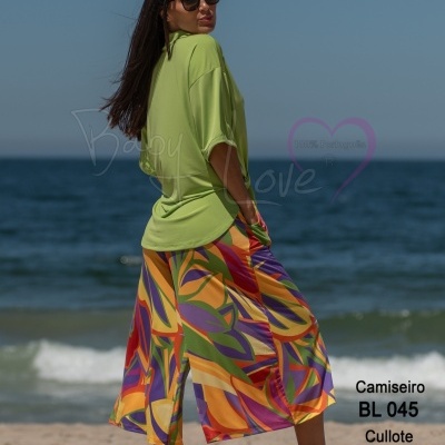 Mulher na praia de camisa verde clara e saia culotte colorida abstrata