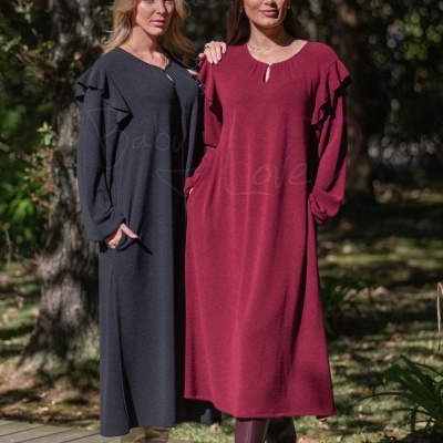 Duas mulheres usam vestidos de malha preto e vinho com folhos, em ambiente exterior com vegetação.