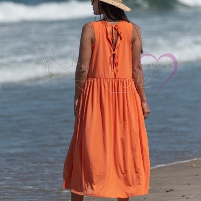 Vestido laranja longo sem mangas com laços nas costas numa praia