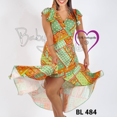 Vestido colorido com padrão verde, laranja e amarelo usado por mulher sorridente com faixa na cabeça