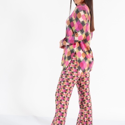 Mulher com roupa de padrão geométrico colorido em fundo branco