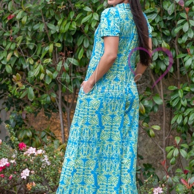 Vestido comprido azul com padrão verde usado por mulher num jardim