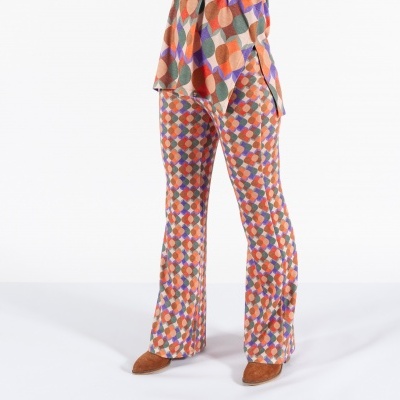 Calças compridas de padrão losangos coloridos com sapatos castanhos.