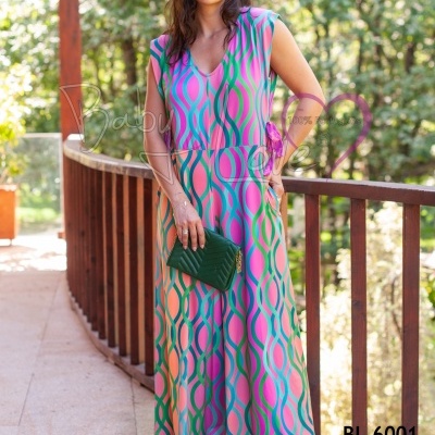 Mulher com macacão colorido e acessórios verdes numa varanda de madeira