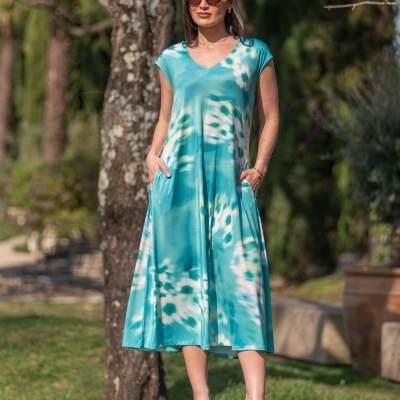 Mulher com vestido azul tie-dye e óculos escuros ao ar livre