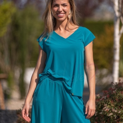 Mulher de túnica azul turquesa com decote em V e pantalonas no exterior