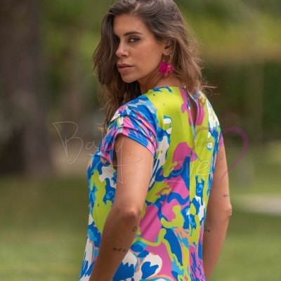 Vestido feminino colorido com padrão floral e abstrato, modelo ao ar livre