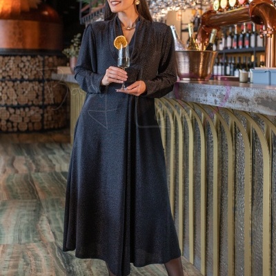 Mulher com vestido preto brilhante segurando copo de champanhe no bar