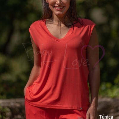 Mulher a usar conjunto vermelho composto por túnica sem mangas e calças em ambiente natural.