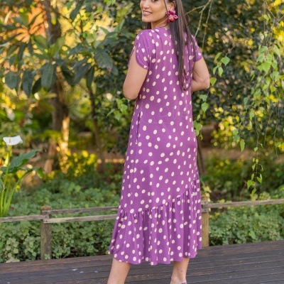 Vestido midi lilás com bolinhas brancas e sapatos de salto alto castanhos em ambiente de jardim