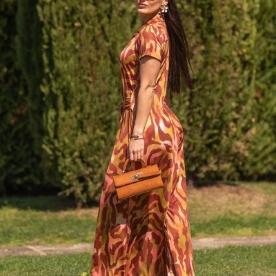 Vestido comprido padrão animal laranja com mala castanha e sandálias castanhas em ambiente exterior