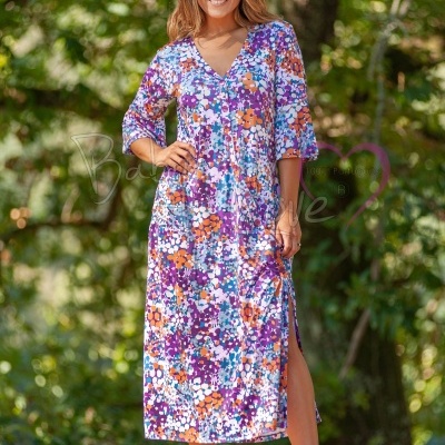 Mulher com vestido comprido floral com mangas três quartos e decote em V em ambiente natural