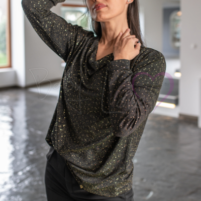 Blusa preta com manchas amarelas, manga comprida, decote em V, calças pretas, modelo em interior com chão de pedra.