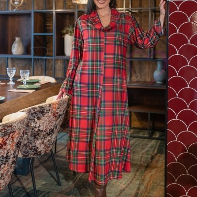 Vestido comprido xadrez vermelho com gola drapeada e botas castanhas em sala decorada